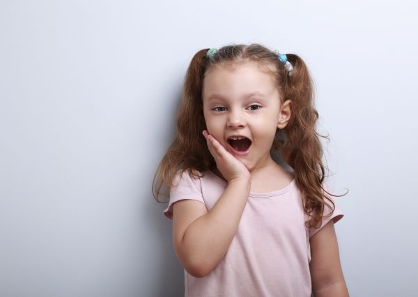 Surprising fun girl looking with open mouth on blue background
